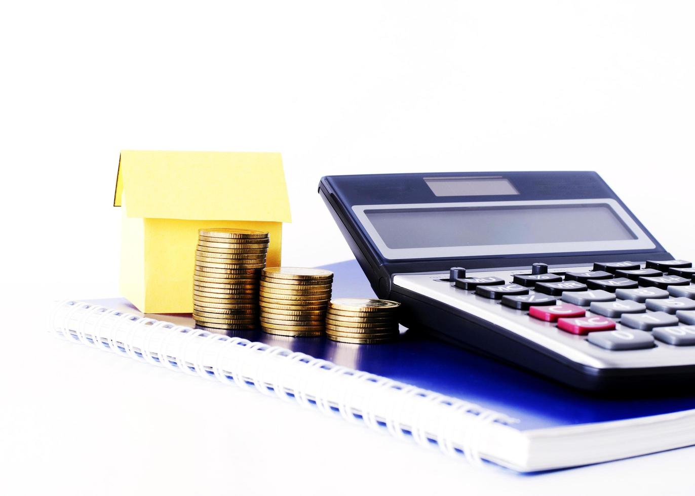 Pila de monedas de dinero y casa de papel y calculadora en el libro diario azul para el concepto de préstamos foto