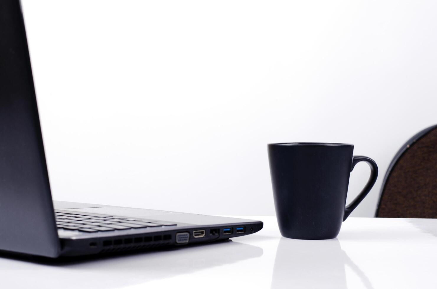 Taza de café negro y portátil sobre fondo blanco. foto