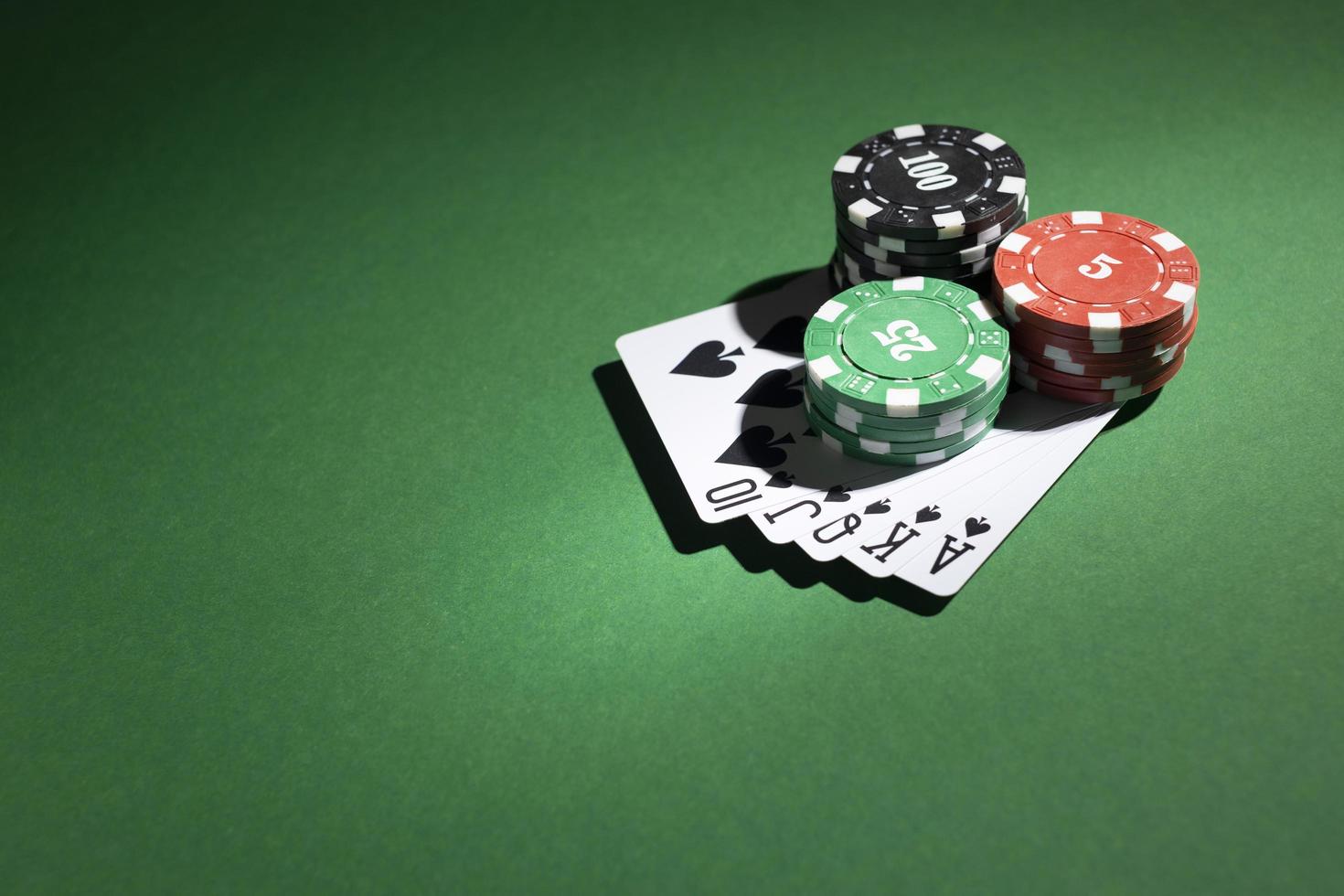 Stacked casino tokens and royal flush on green background photo