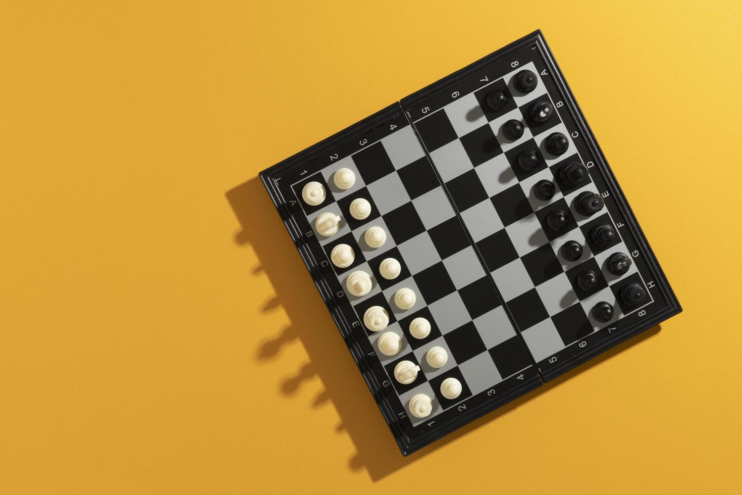 Top view of chess board with pieces on yellow background photo