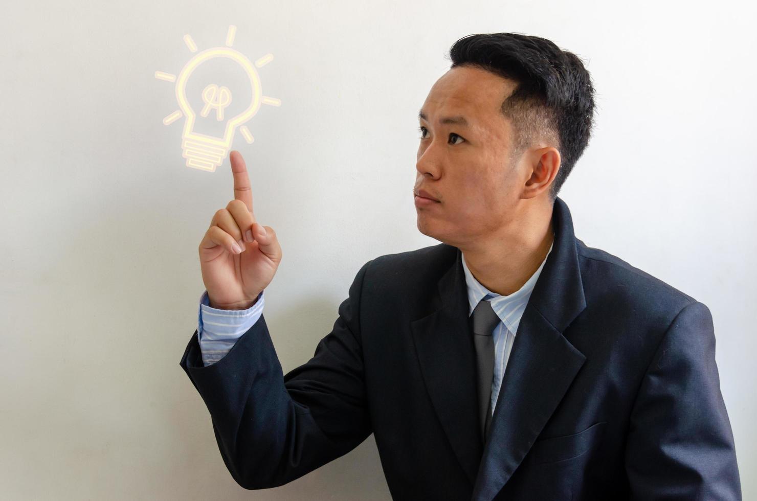 Side portrait of businessman pointing to a light bulb. Positive thinking or positivity for creative ideas. Business process concept. photo