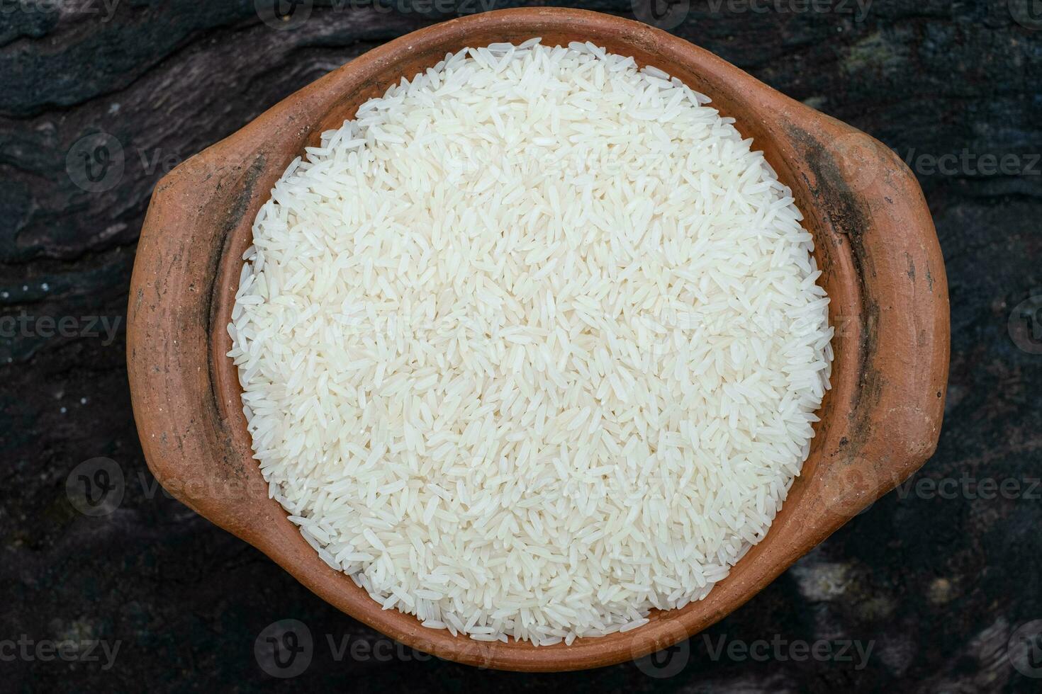 Arroz jazmín en una olla de barro sobre un fondo de madera foto