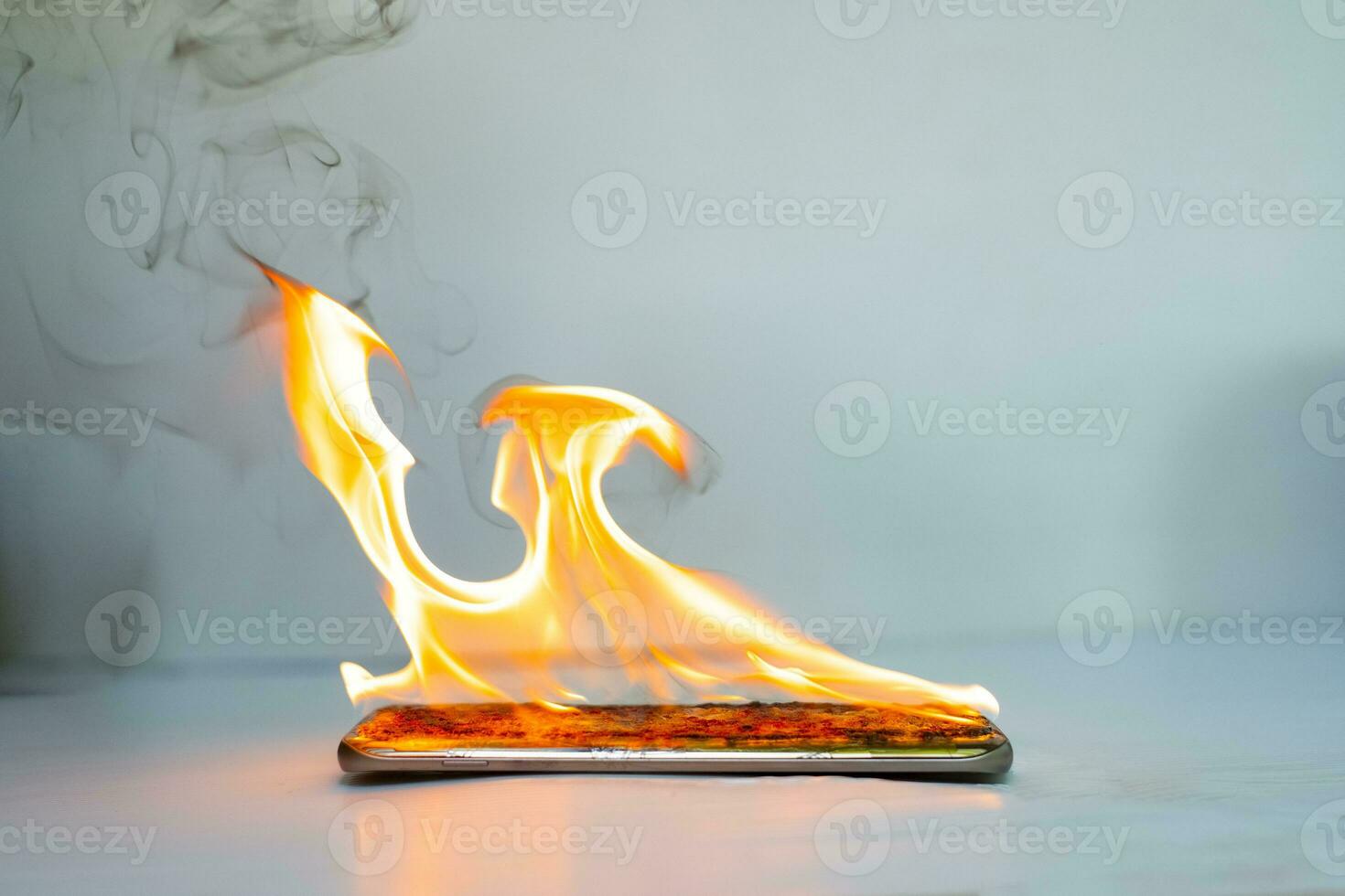 La pantalla del teléfono inteligente está agrietada y en llamas con un fondo borroso foto