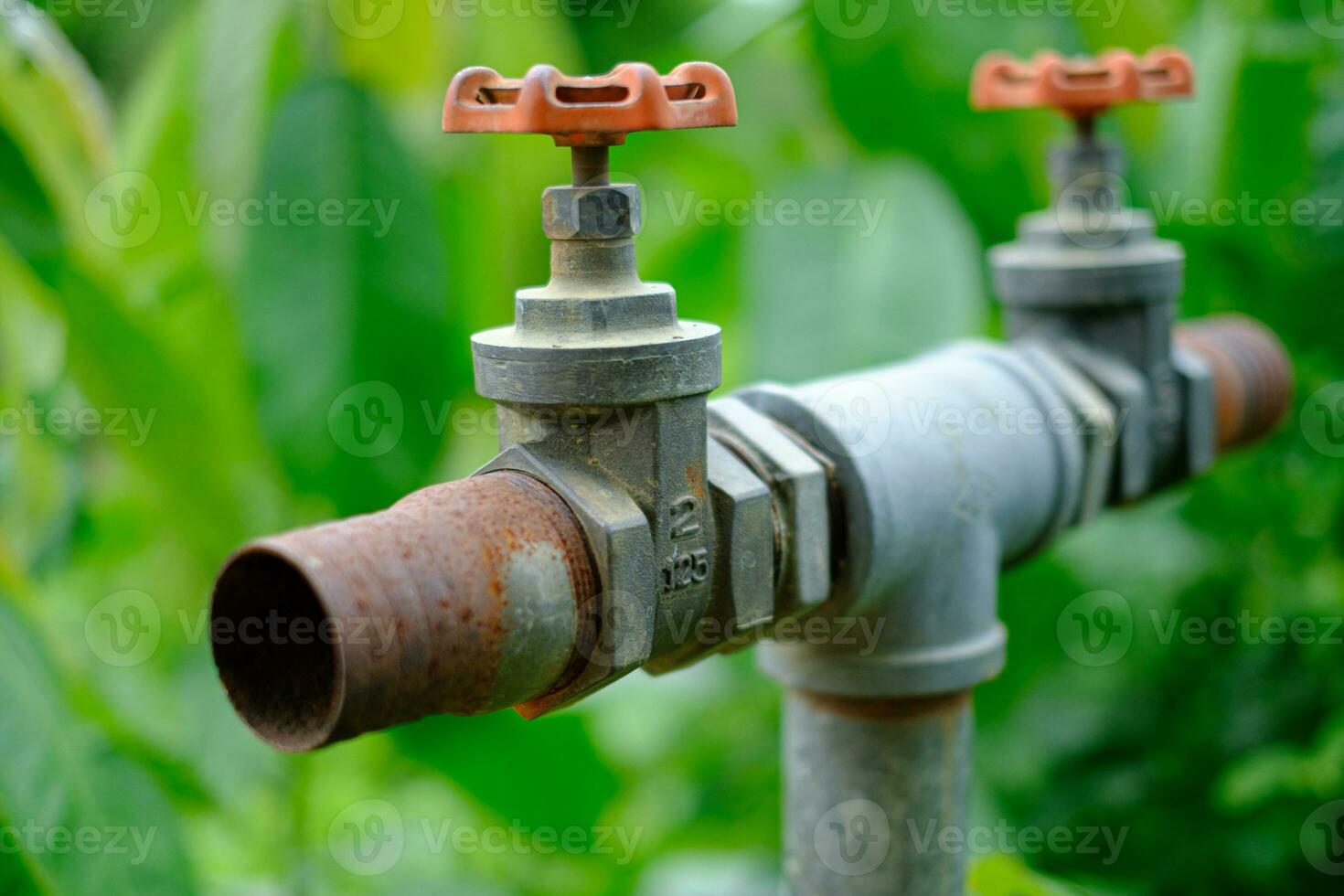 Válvula de compuerta en la tubería en los sistemas de riego controlan el agua para cerrar el lugar antiguo con un fondo borroso foto