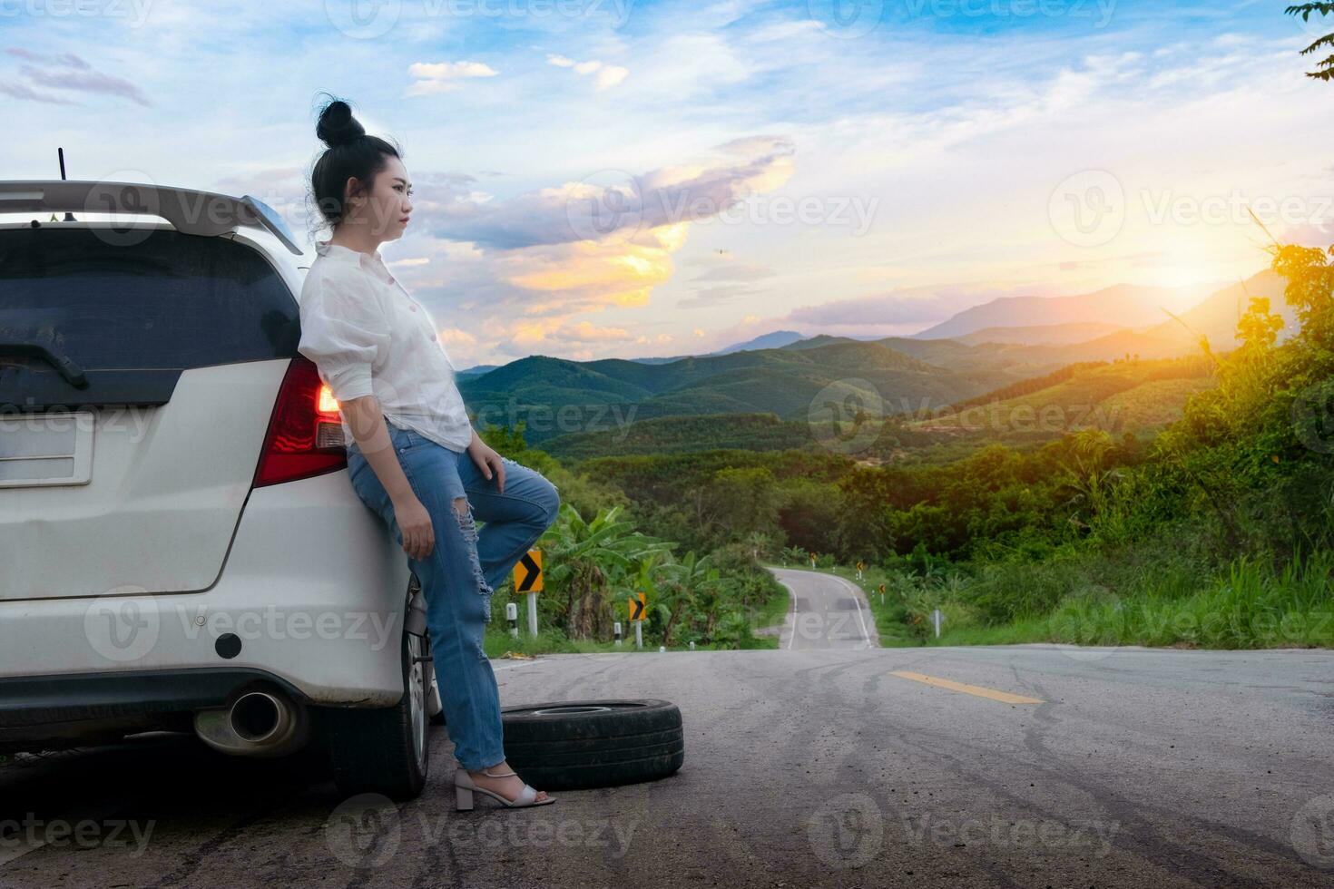 Hermosa jovencita de pie cerca del coche para pedir ayuda en la vía pública foto