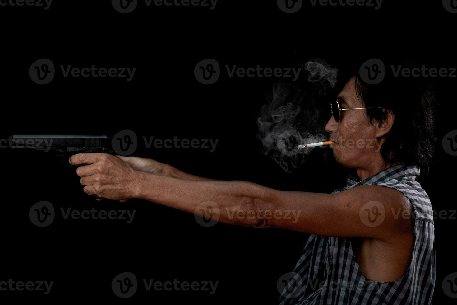 Retrato anciano asiático sosteniendo una pistola sobre un fondo negro foto