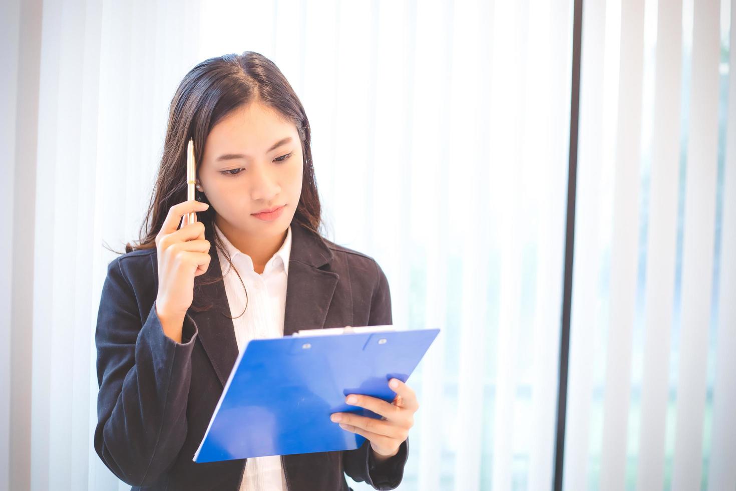 Asian woman looking at clip board for work photo