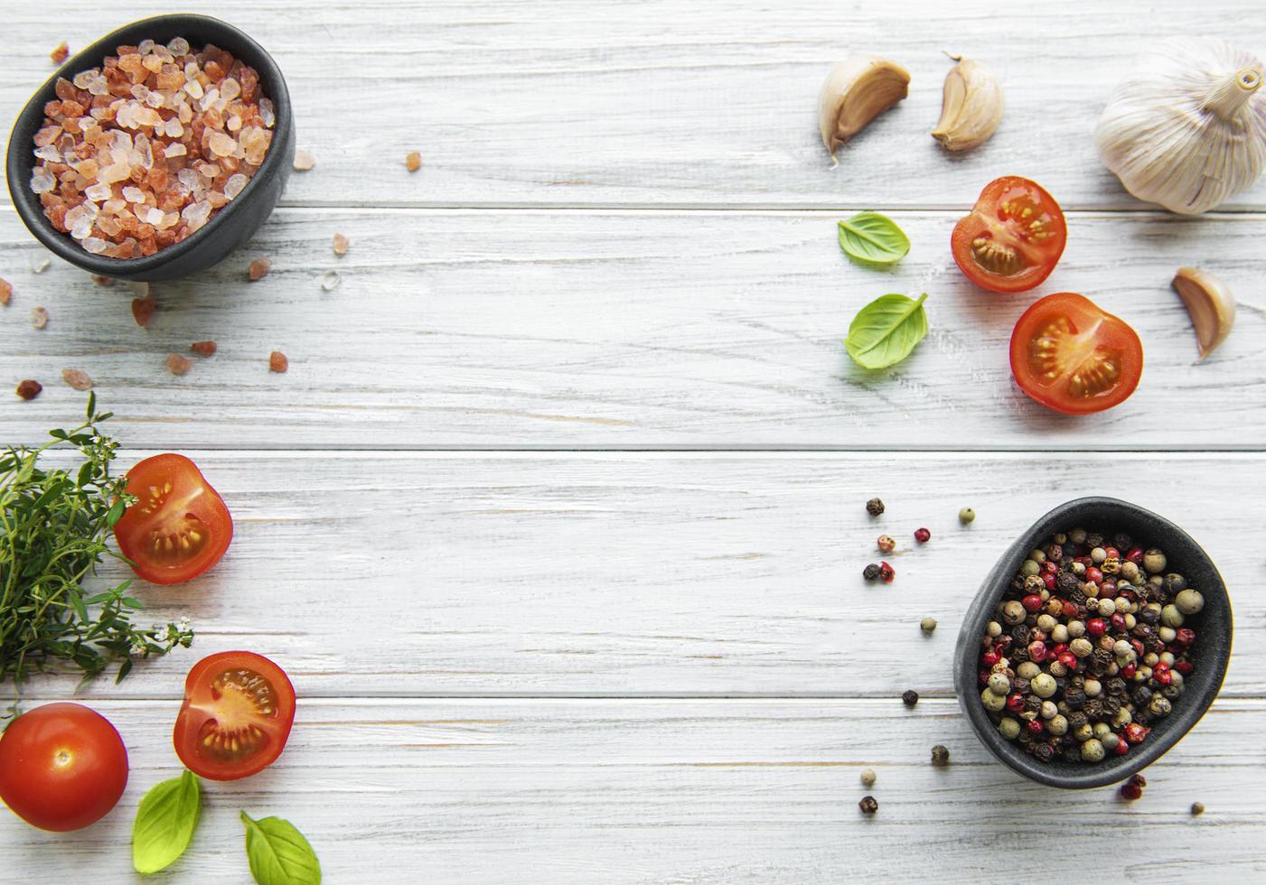 Tomate, albahaca y pimiento con ajo sobre fondo blanco de madera foto