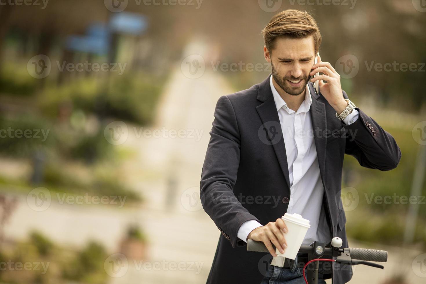 hombre en scooter con café y un teléfono foto
