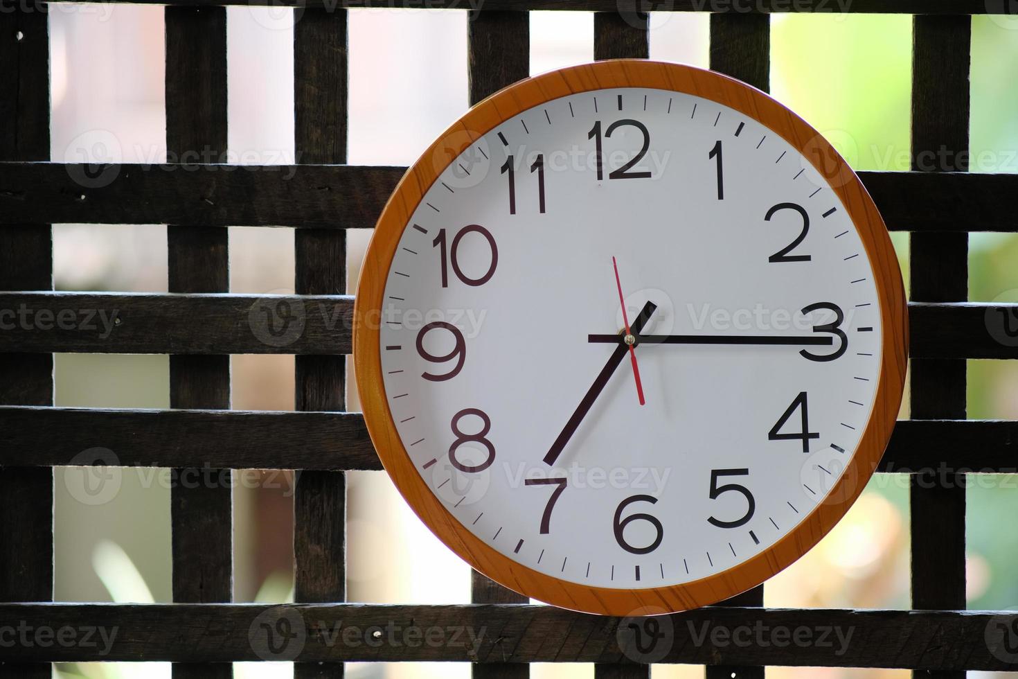 Reloj de pared sobre fondo de madera y concepto de tiempo foto