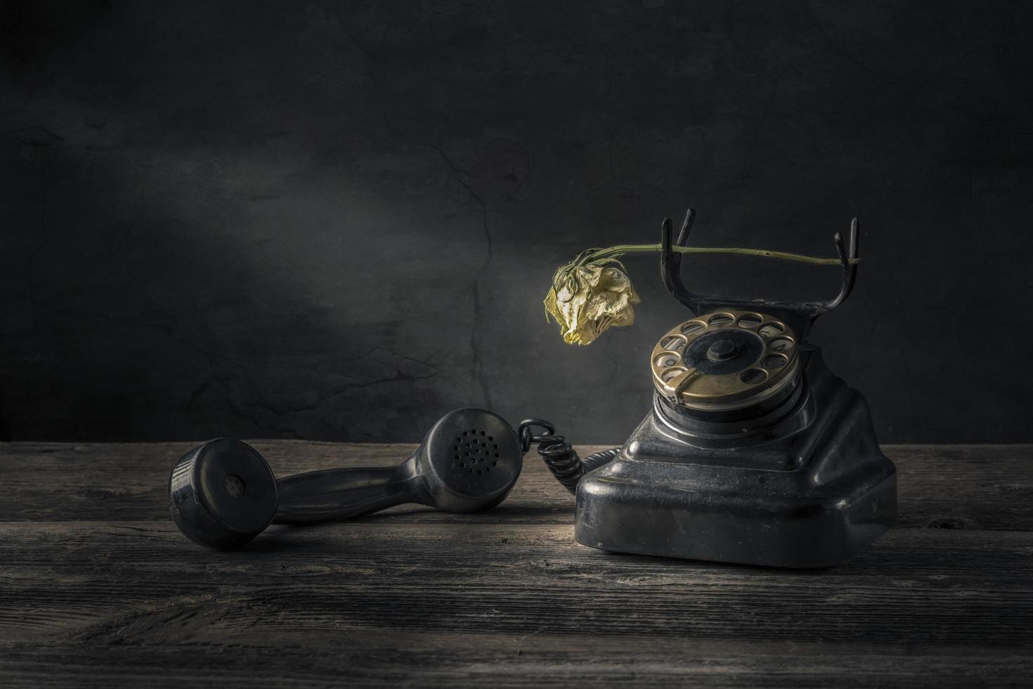 Vintage black phone on old wooden table background photo