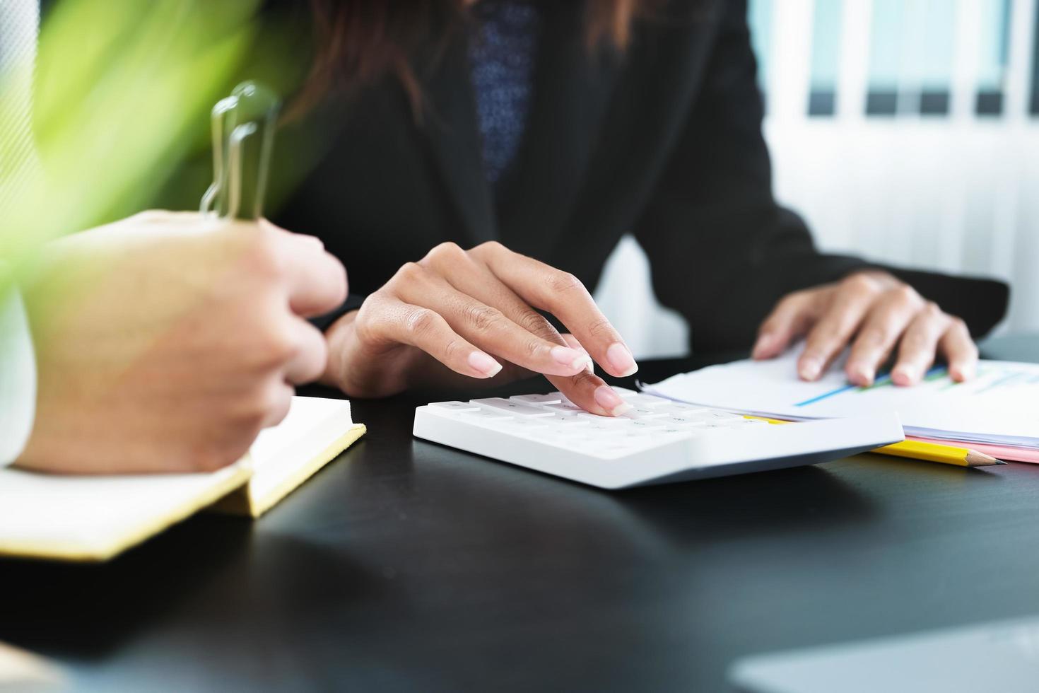 Two young business executives are discussing to change their business concept to increase profits and the strength of their business with using calculator and laptop for work. photo