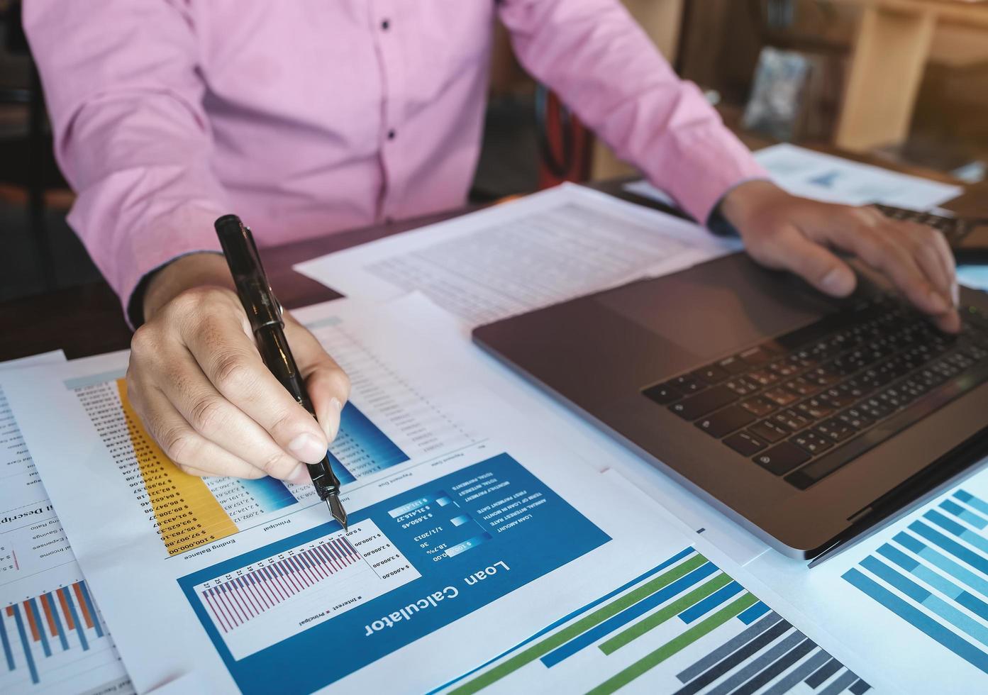 Bookkeeper accounting Concepts, Male hand holding pen pointing to loan application with computer laptop to working , inspector accountant concept. photo