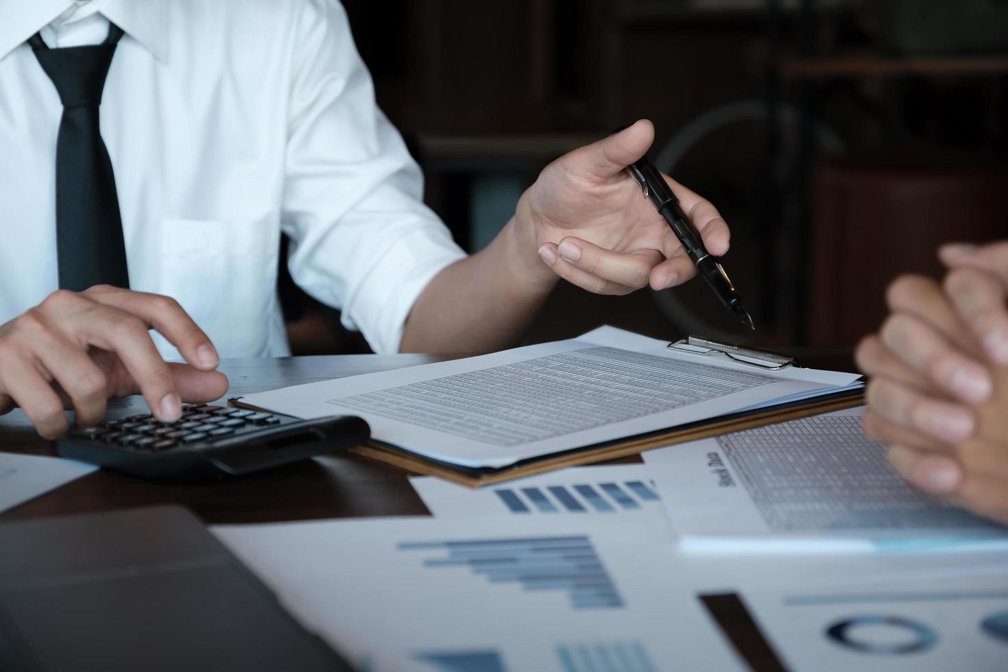 discusiones de investigación económica, equipo de negocios que analiza tablas y gráficos de ingresos para planificar el concepto de marketing con el uso de la calculadora para el análisis. foto