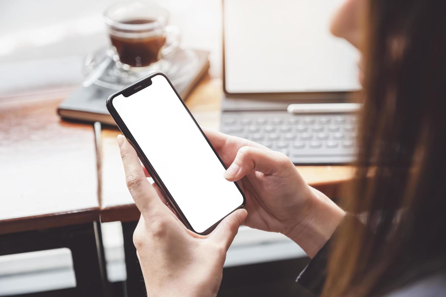 mujer de negocios con smartphone con tableta en caffee shop. teléfono inteligente o móvil con pantalla en blanco y puede agregar sus textos u otros, concepto de tecnología. foto