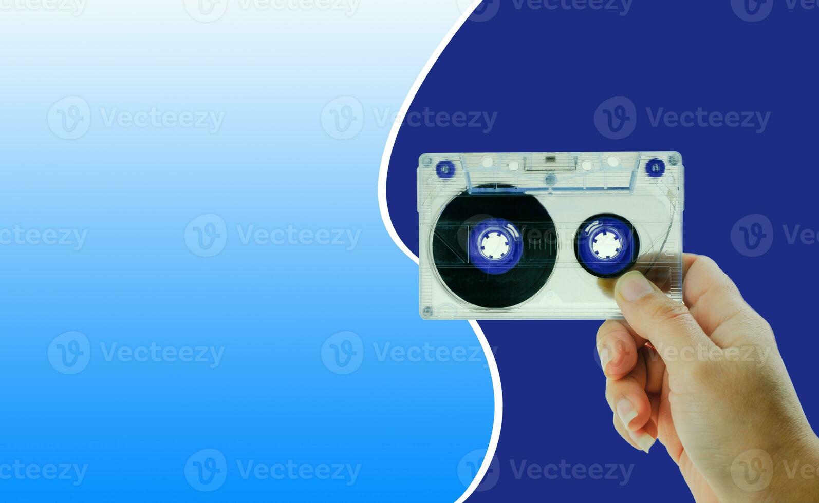 Woman's hand holding tape cassette at blue background photo