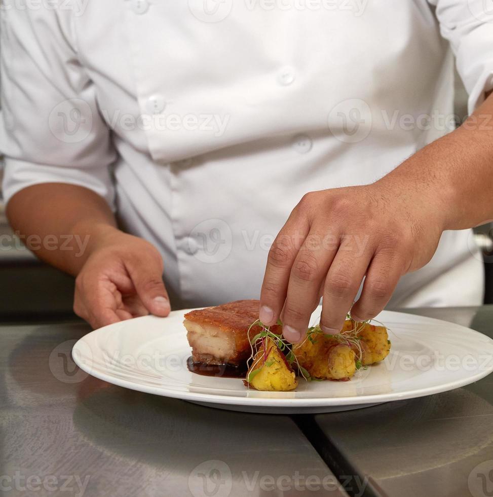 Chef decorando comida tradicional peruana llamada chicharron de panceta de cerdo foto