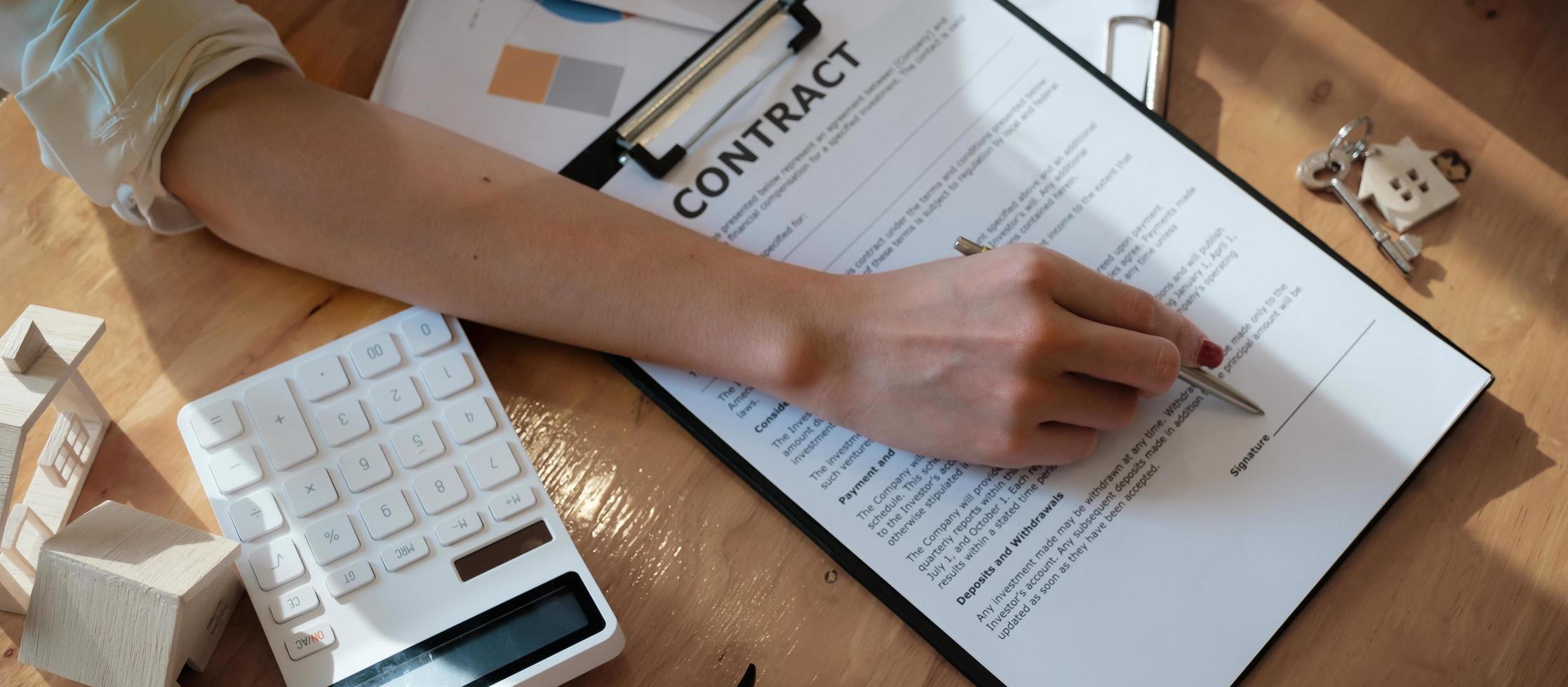 Businesswoman putting signature on a contract at a business meeting with business partners. photo