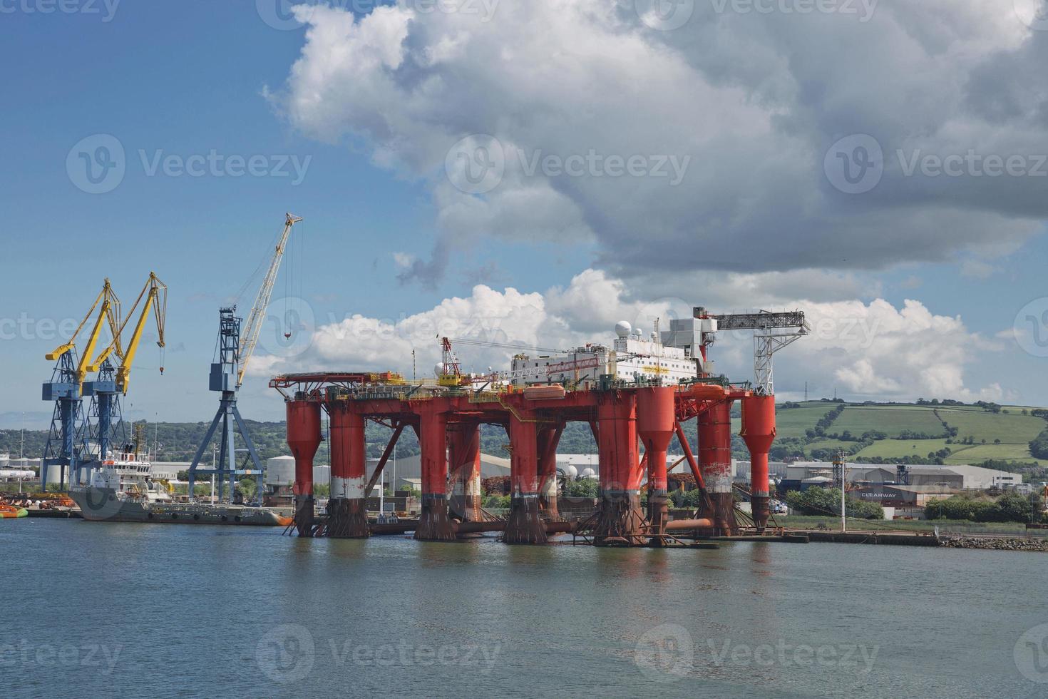 Grandes grúas industriales cargando un buque portacontenedores en el puerto de Belfast en Irlanda foto