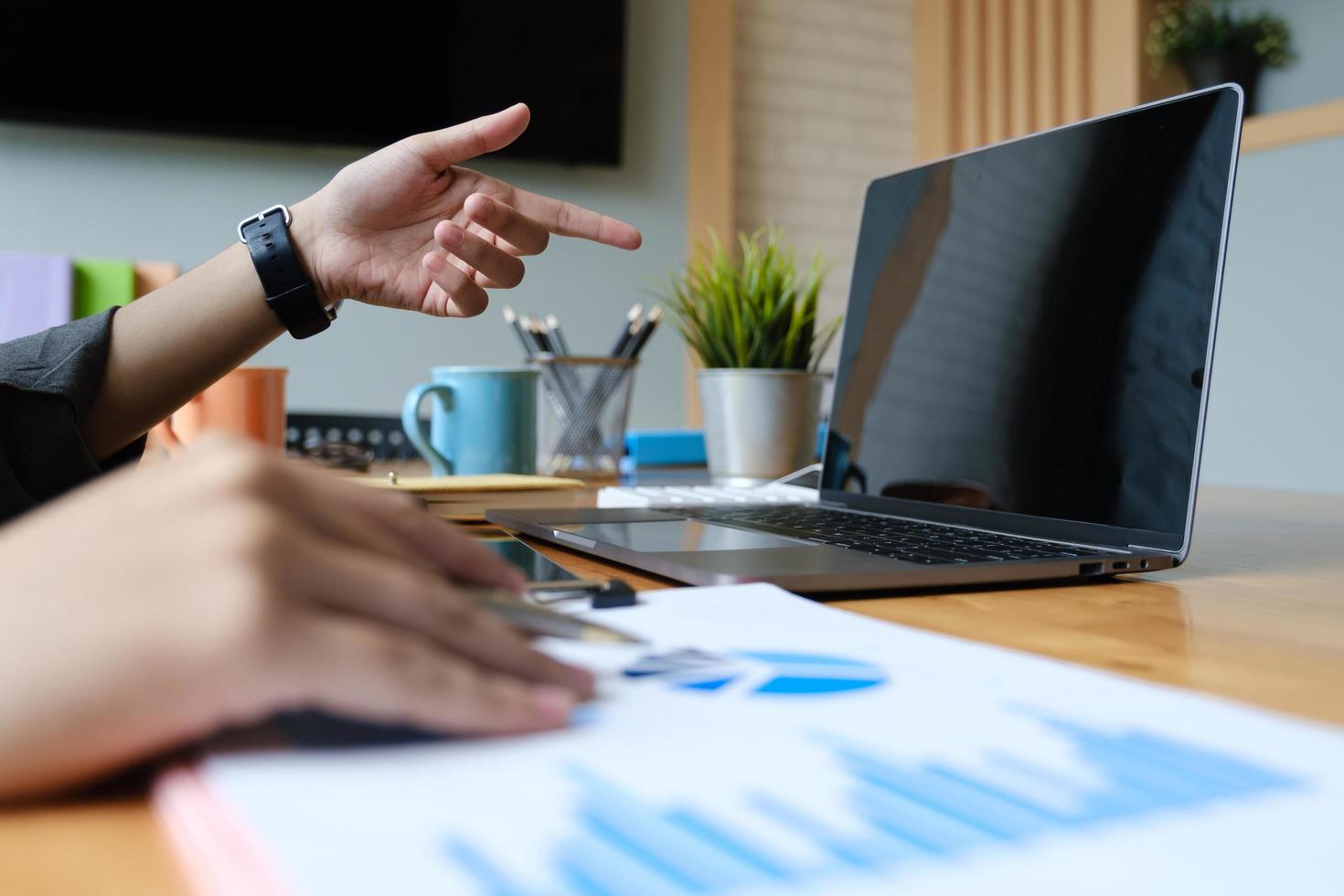 Close up hand of businesswoman pointing and analyzing charts with a laptop computer photo