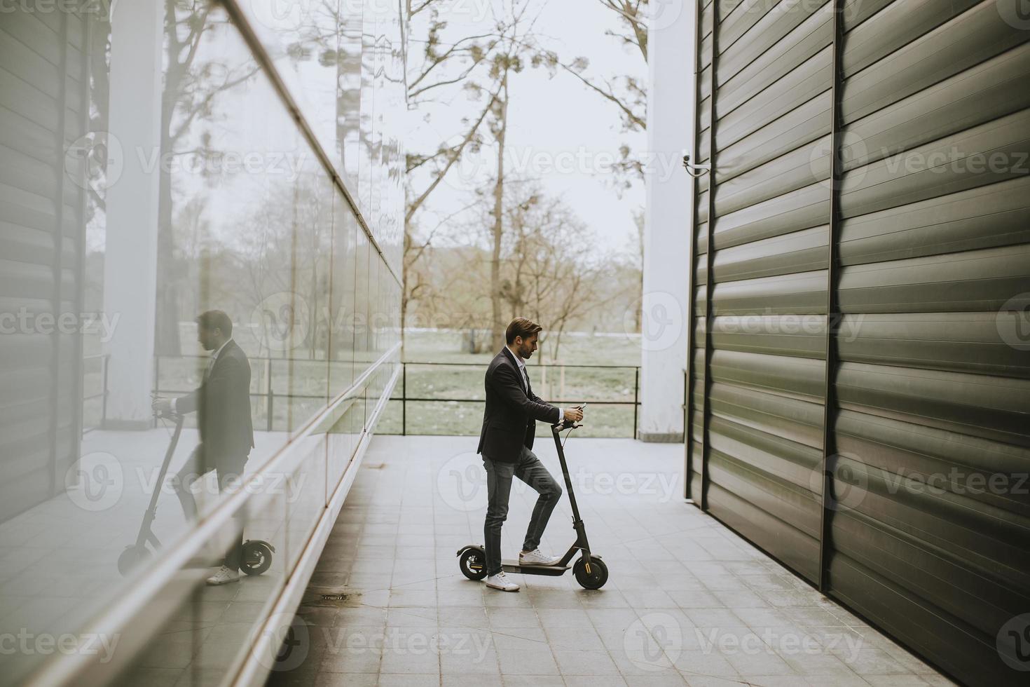 Businessman on a scooter between buildings photo