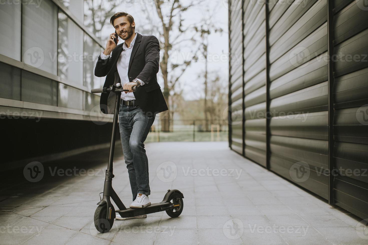 Man holding a scooter and talking on phone photo