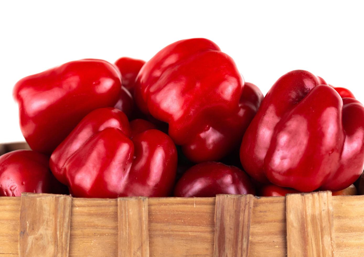 Rd sweet bell peppers in a basket isolated on white background photo