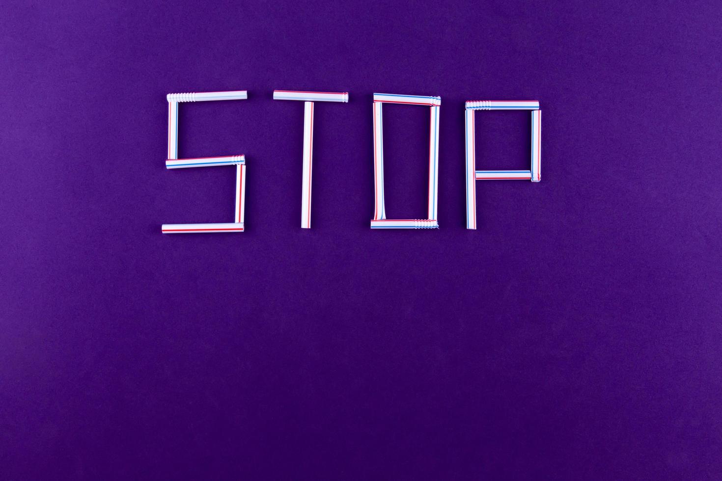 La palabra stop hecha de tubos de plástico sobre un fondo violeta. foto