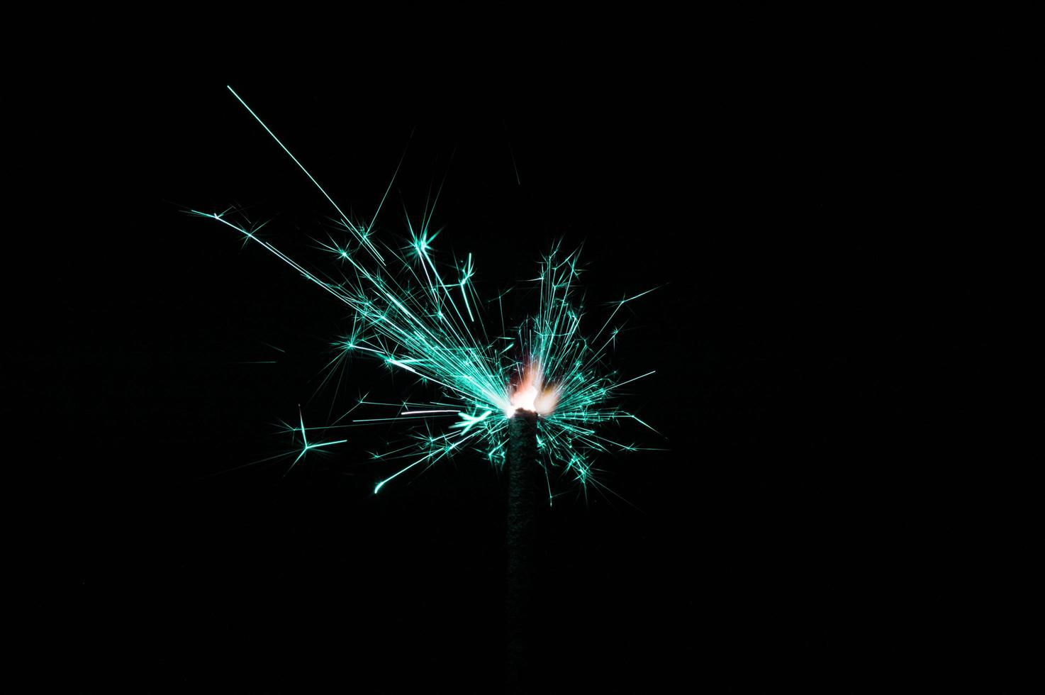 Sparkler in turquoise and white light on a black background photo