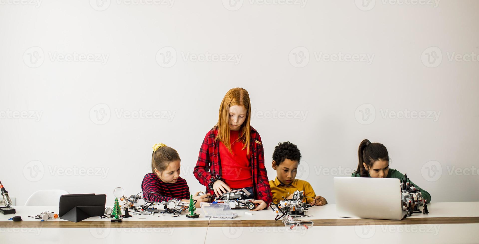 Happy kids programming electric toys and robots at robotics classroom photo