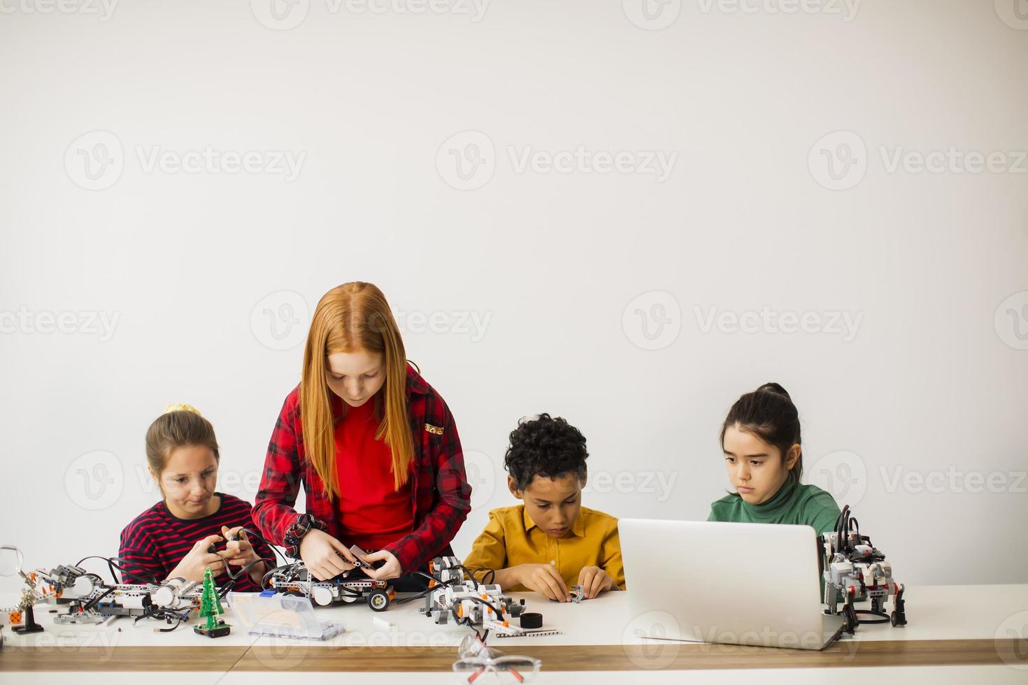 Happy kids programming electric toys and robots at robotics classroom photo