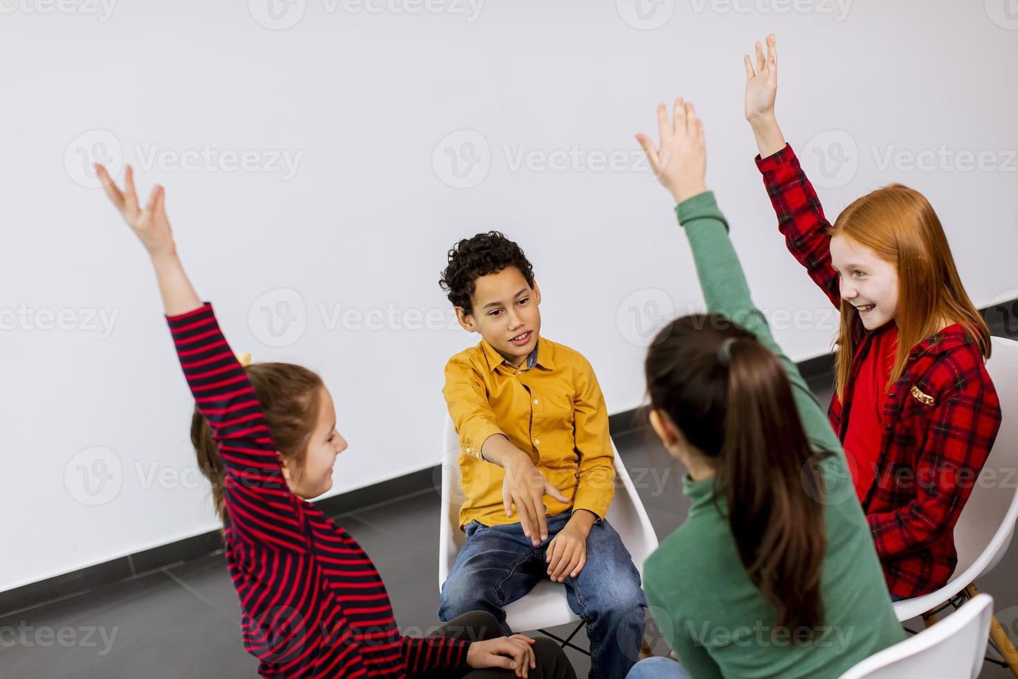 Portrait of cute little kids in jeans  talking and sitting in chairs against white wall photo