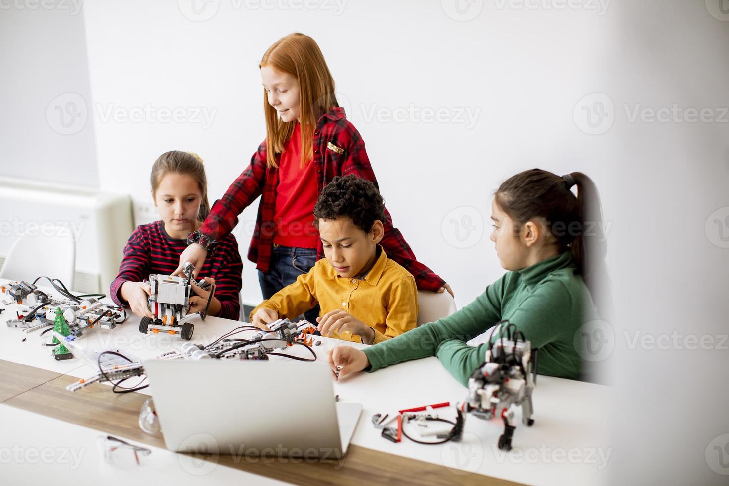 Happy kids programming electric toys and robots at robotics classroom photo