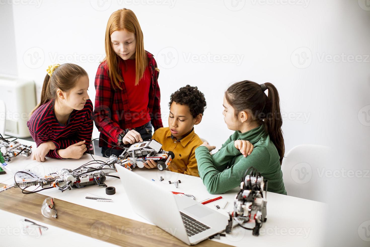 Happy kids programming electric toys and robots at robotics classroom ...