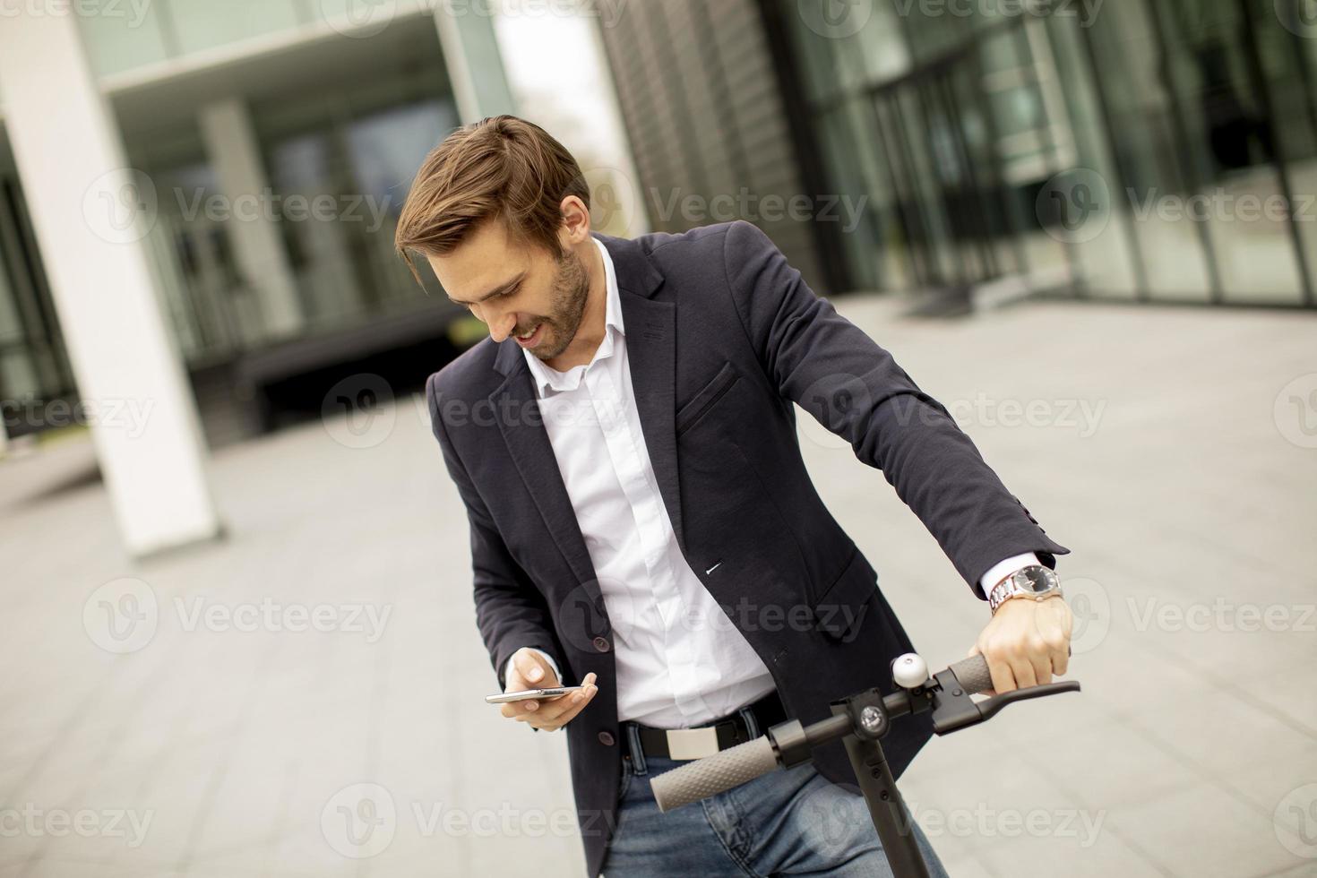 Young businessman using mobile phone on electric scooter photo