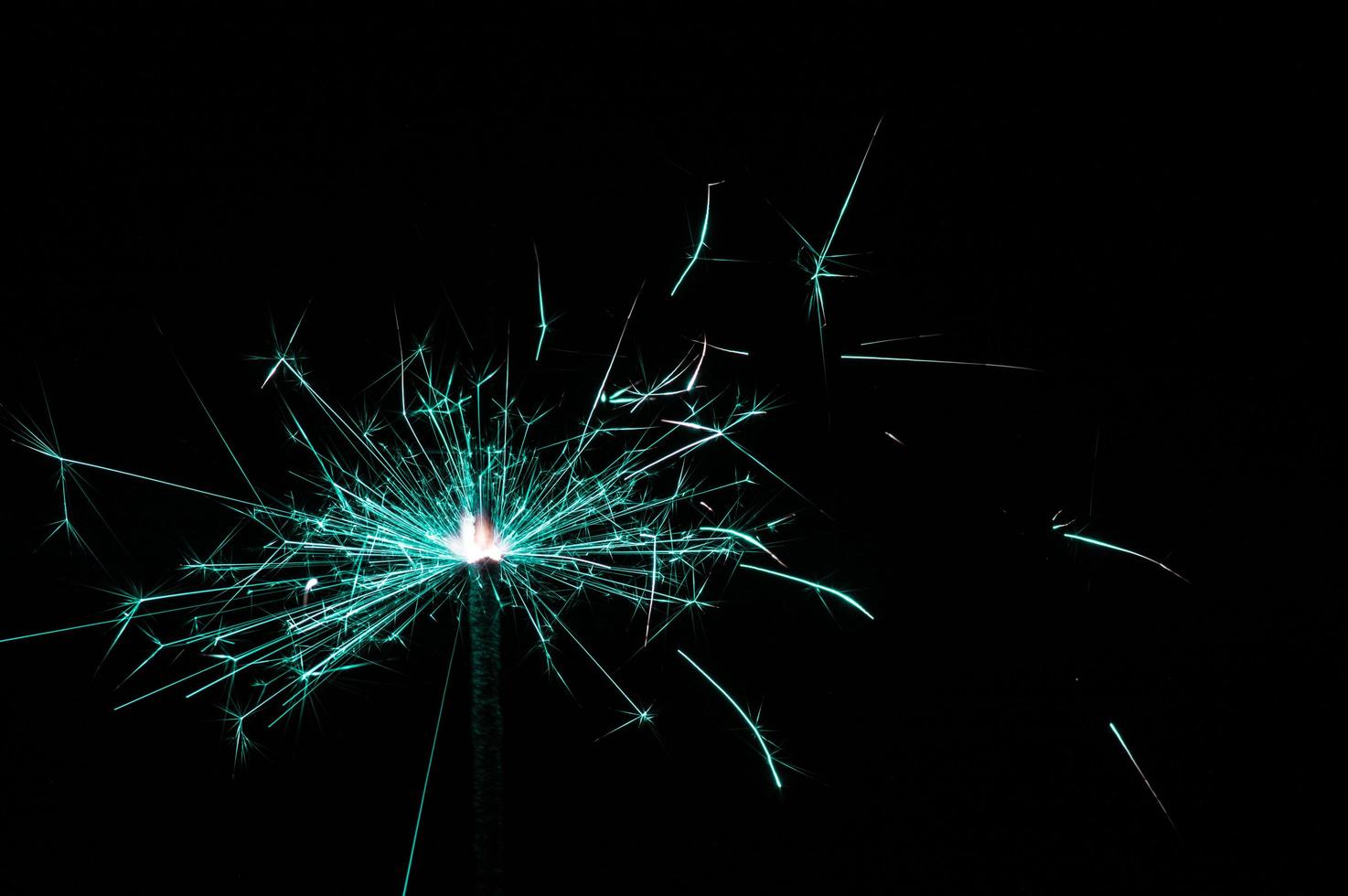 Sparkler in turquoise and white light on a black background photo