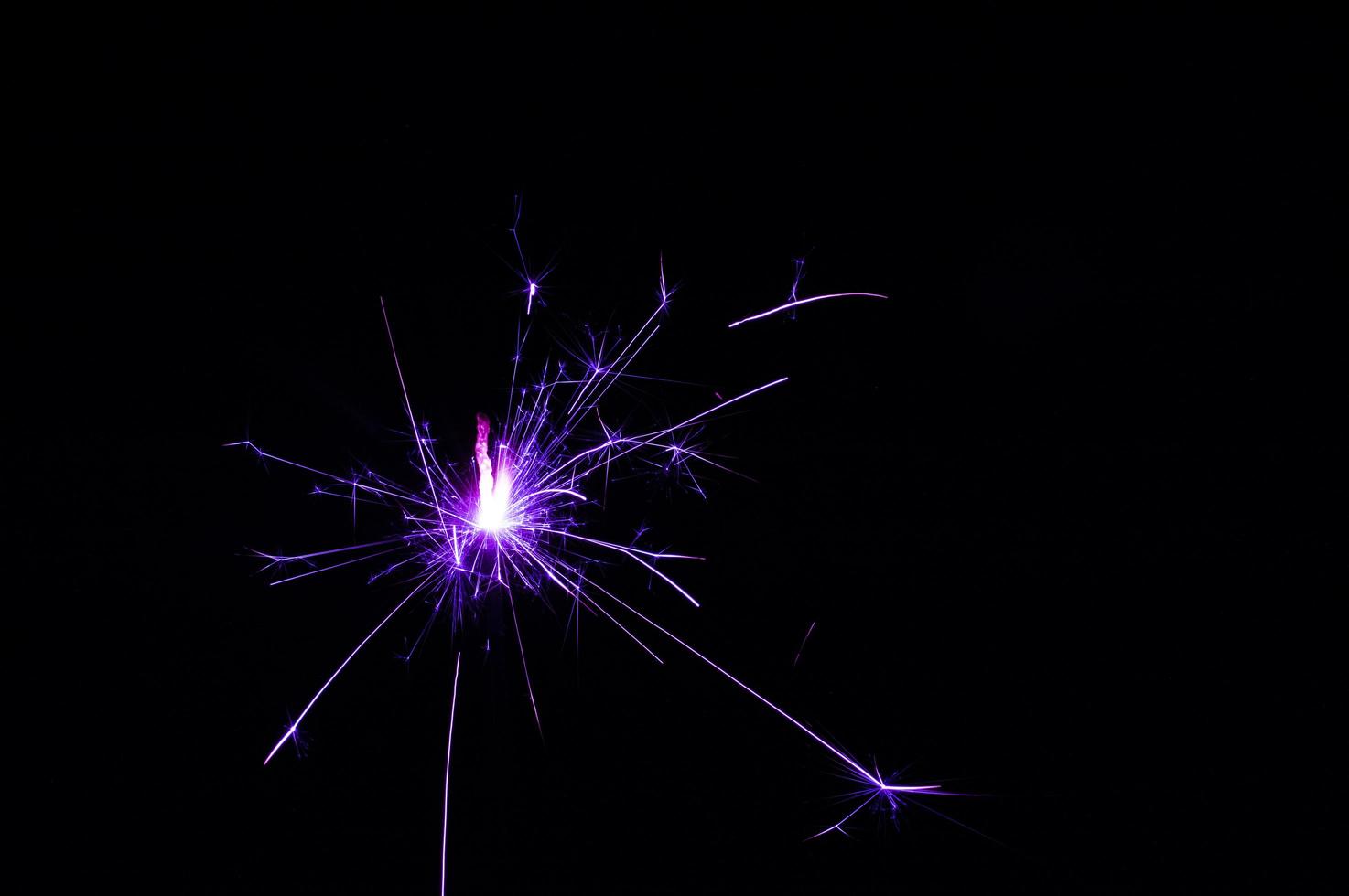 Sparkler in violet and white light on a black background photo