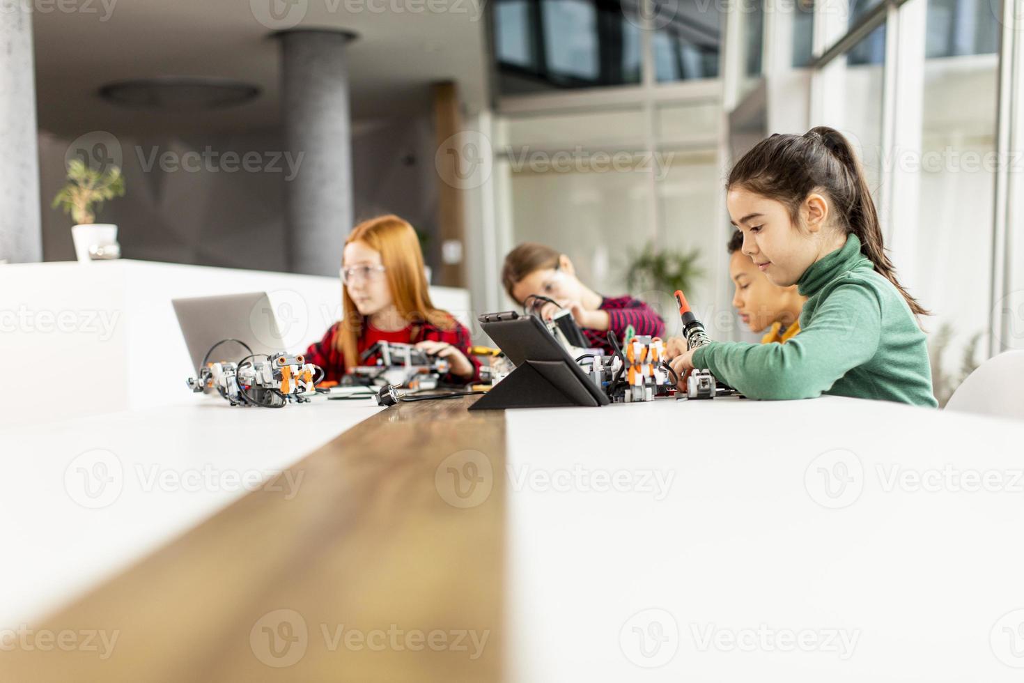 Happy kids programming electric toys and robots at robotics classroom photo