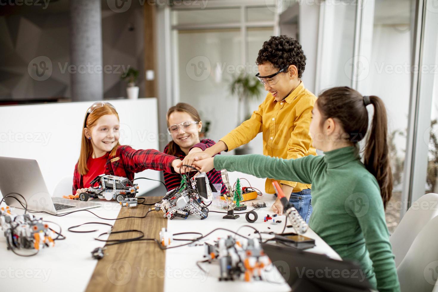 Niños felices programando juguetes eléctricos y robots en el aula de robótica foto