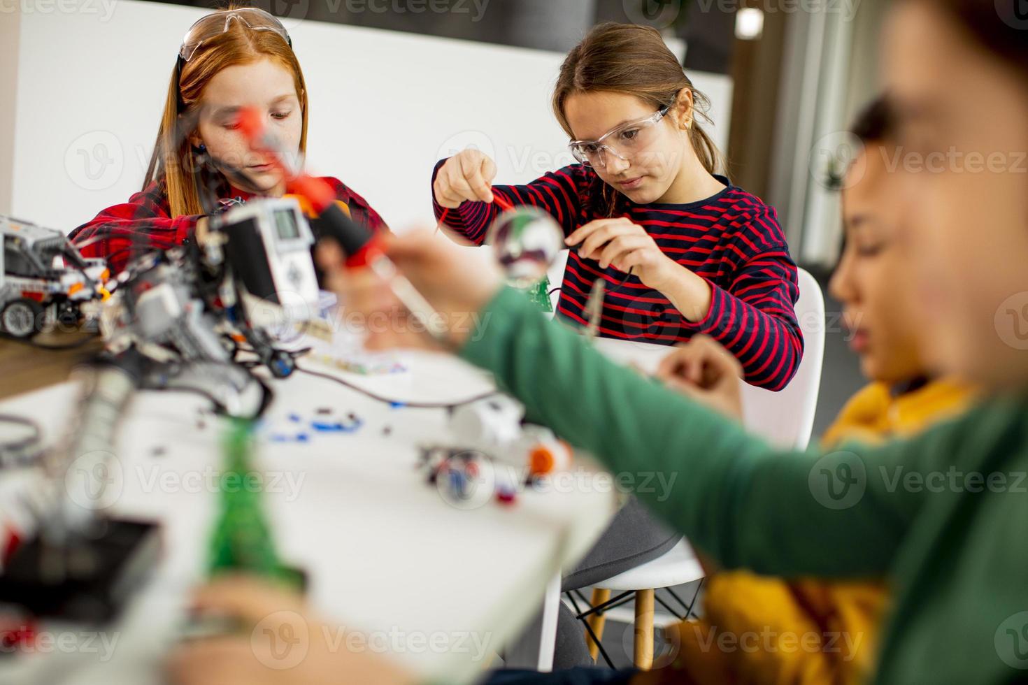 Niños felices programando juguetes eléctricos y robots en el aula de robótica foto