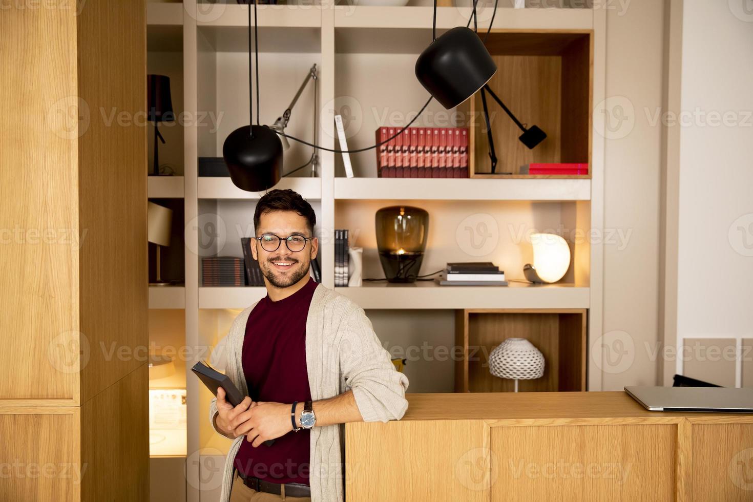 apuesto joven en ropa casual y con anteojos sosteniendo un libro foto