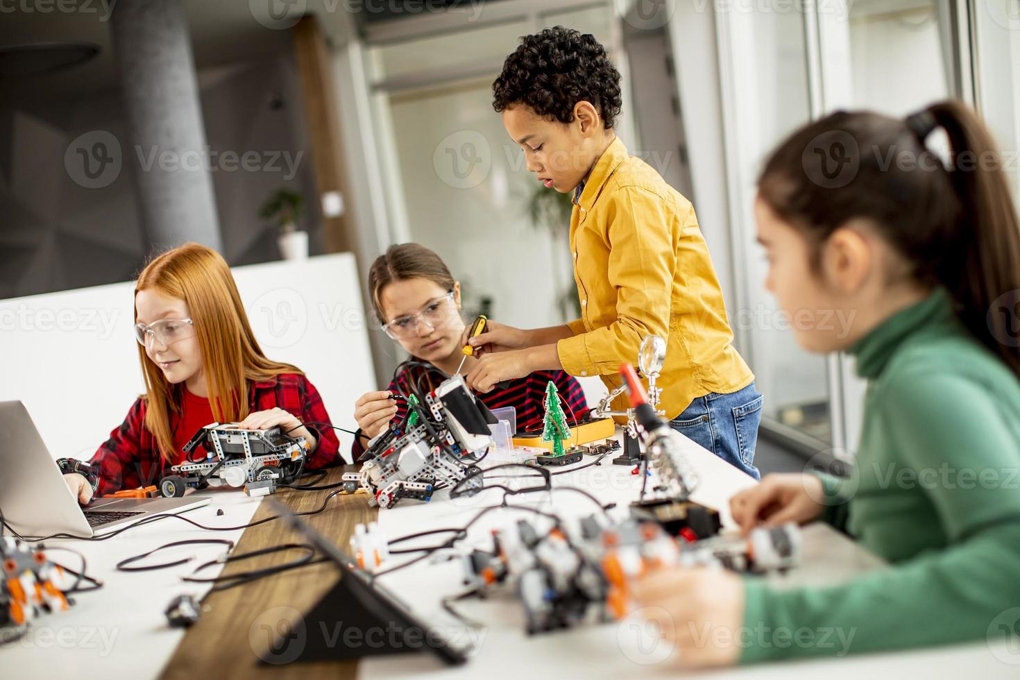 Happy kids programming electric toys and robots at robotics classroom photo