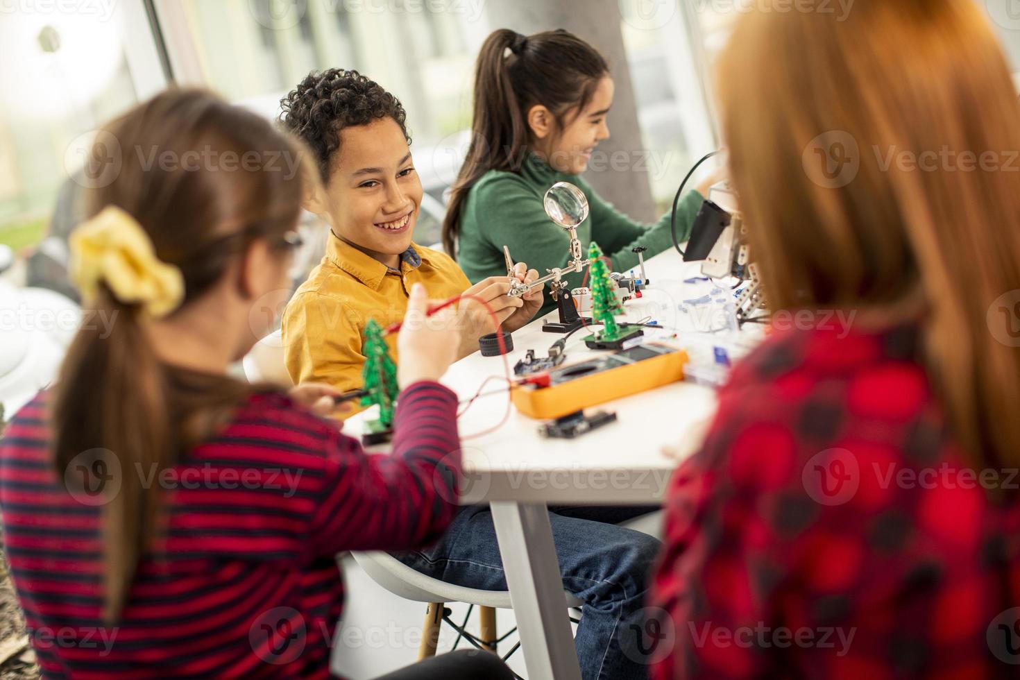 Happy kids programming electric toys and robots at robotics classroom photo