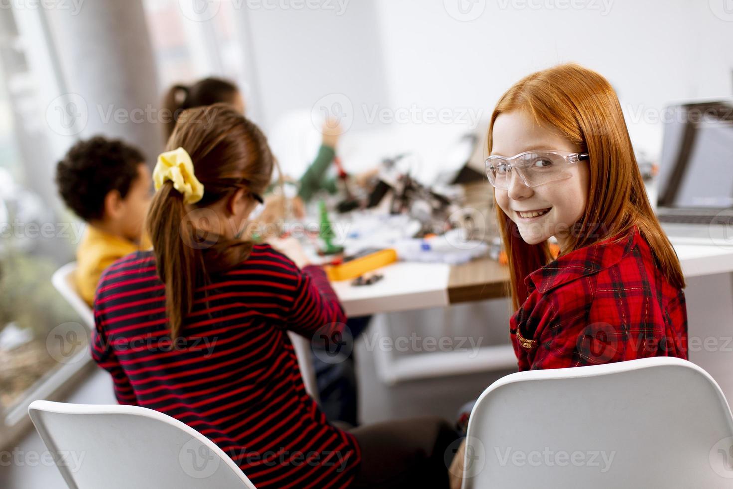 Happy kids programming electric toys and robots at robotics classroom photo