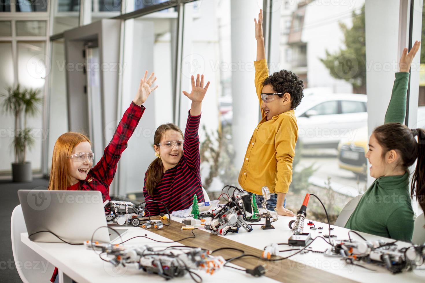 Niños felices programando juguetes eléctricos y robots en el aula de robótica foto