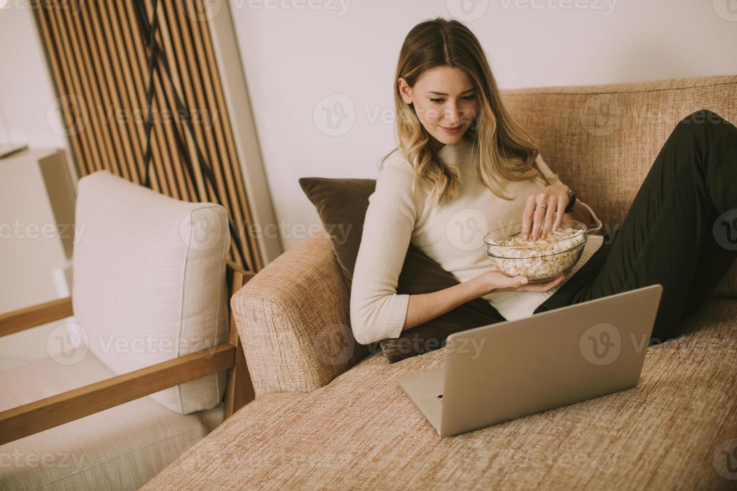 Mujer hermosa joven usando una computadora portátil en casa foto