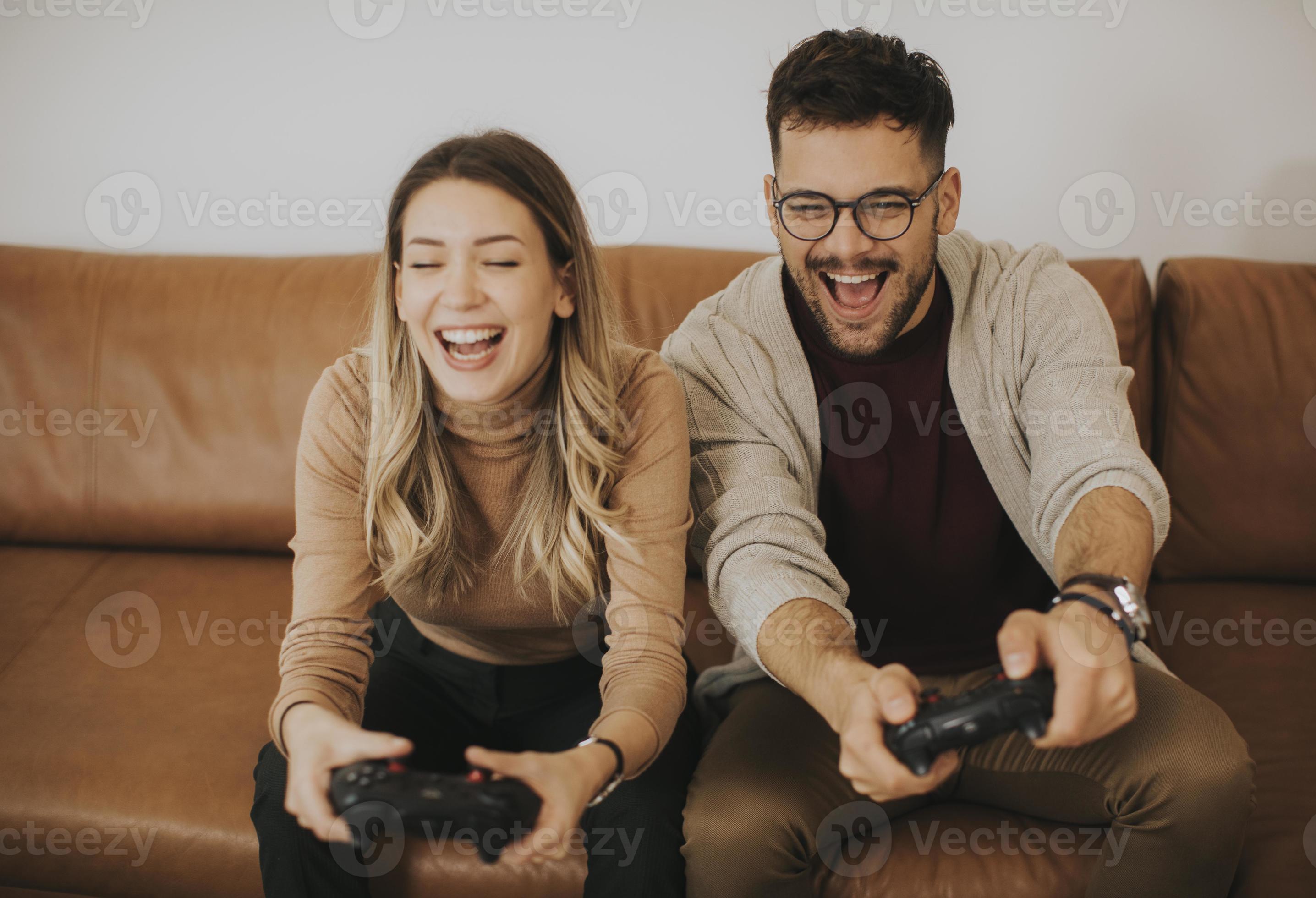 Happy Couple Sitting On The Sofa Playing Video Games Using