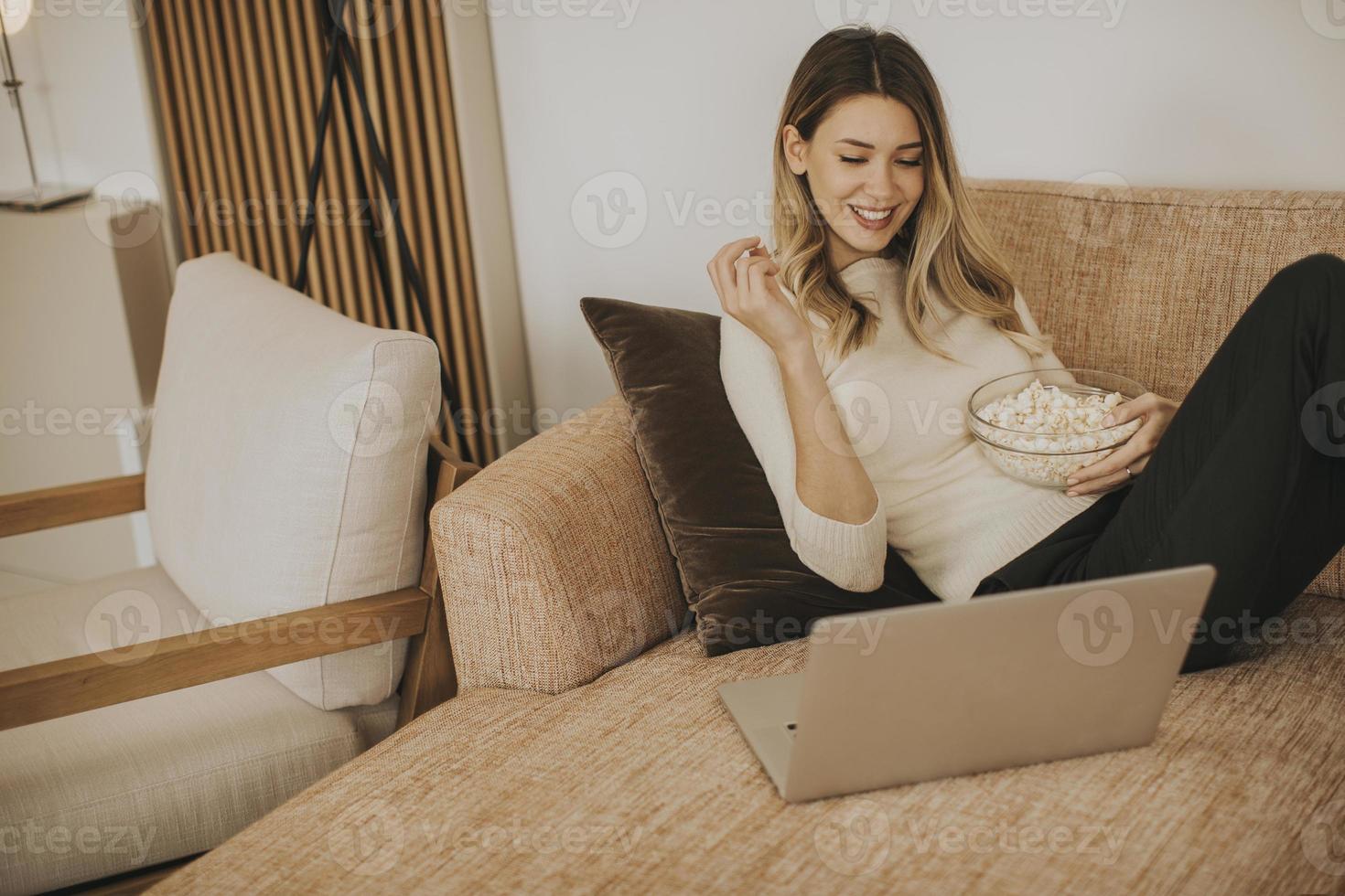 Mujer hermosa joven usando una computadora portátil en casa foto