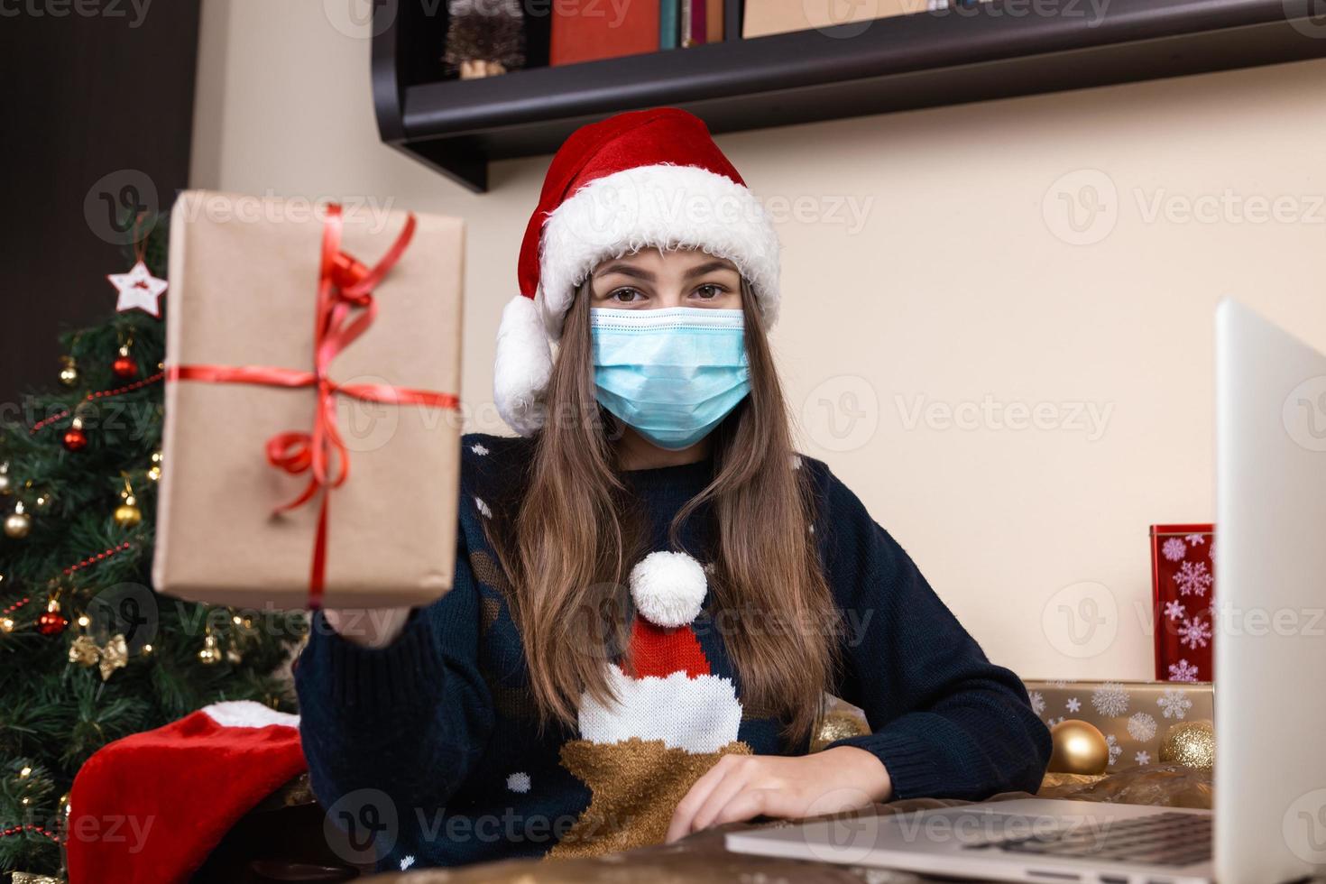 niña con sombrero de santa claus usando laptop para videollamadas a amigos y padres foto