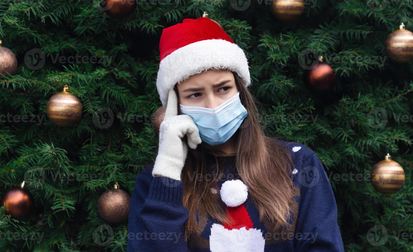 Close-up portrait of woman wearing a santa claus hat and medical mask with emotion photo